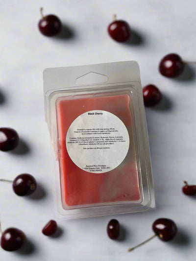 Red cherry wax melt snap bar in clamshell packaging, surrounded by fresh cherries on a white surface.
